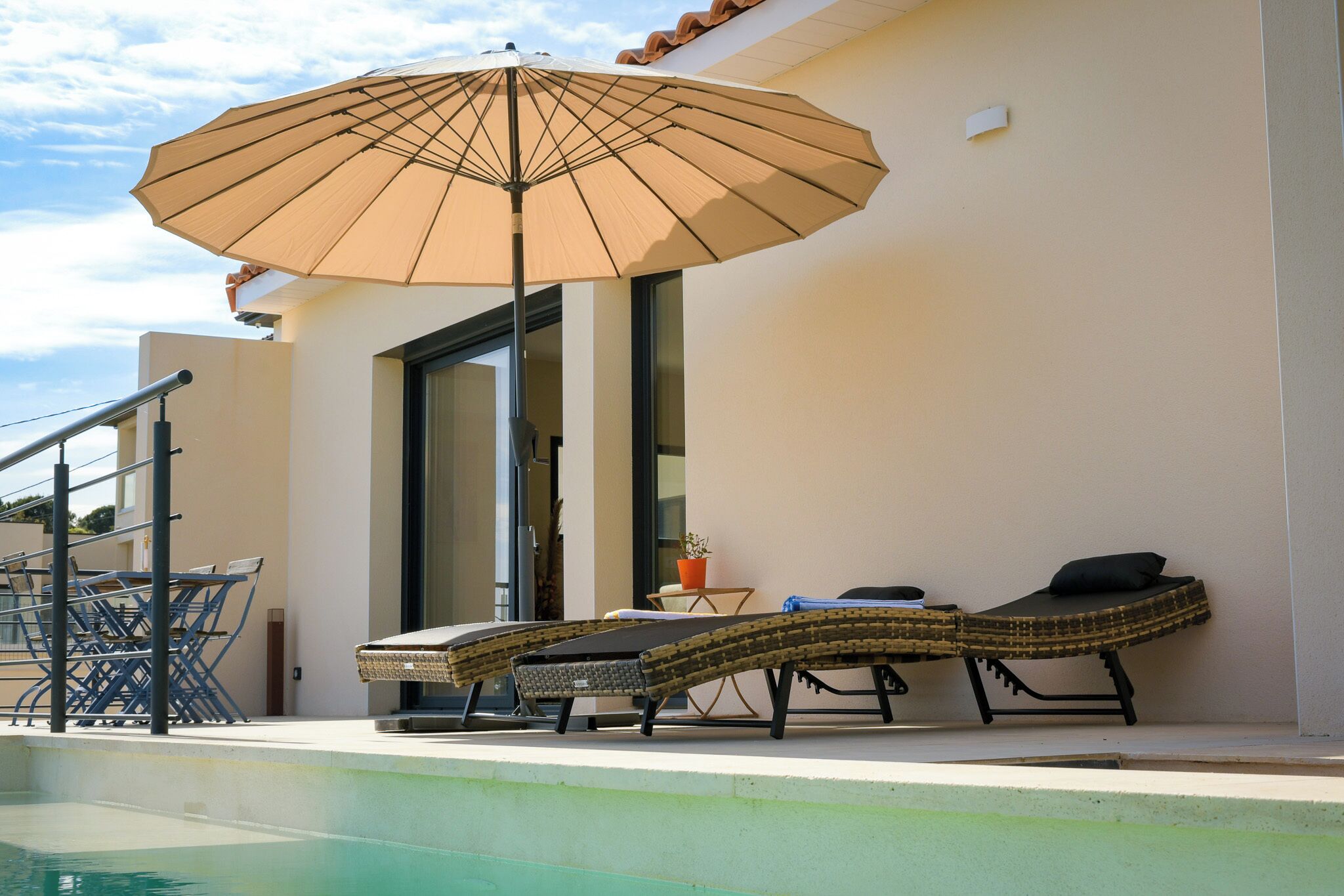 Ein Poolbereich mit Liegestühlen und einem Sonnenschirm.