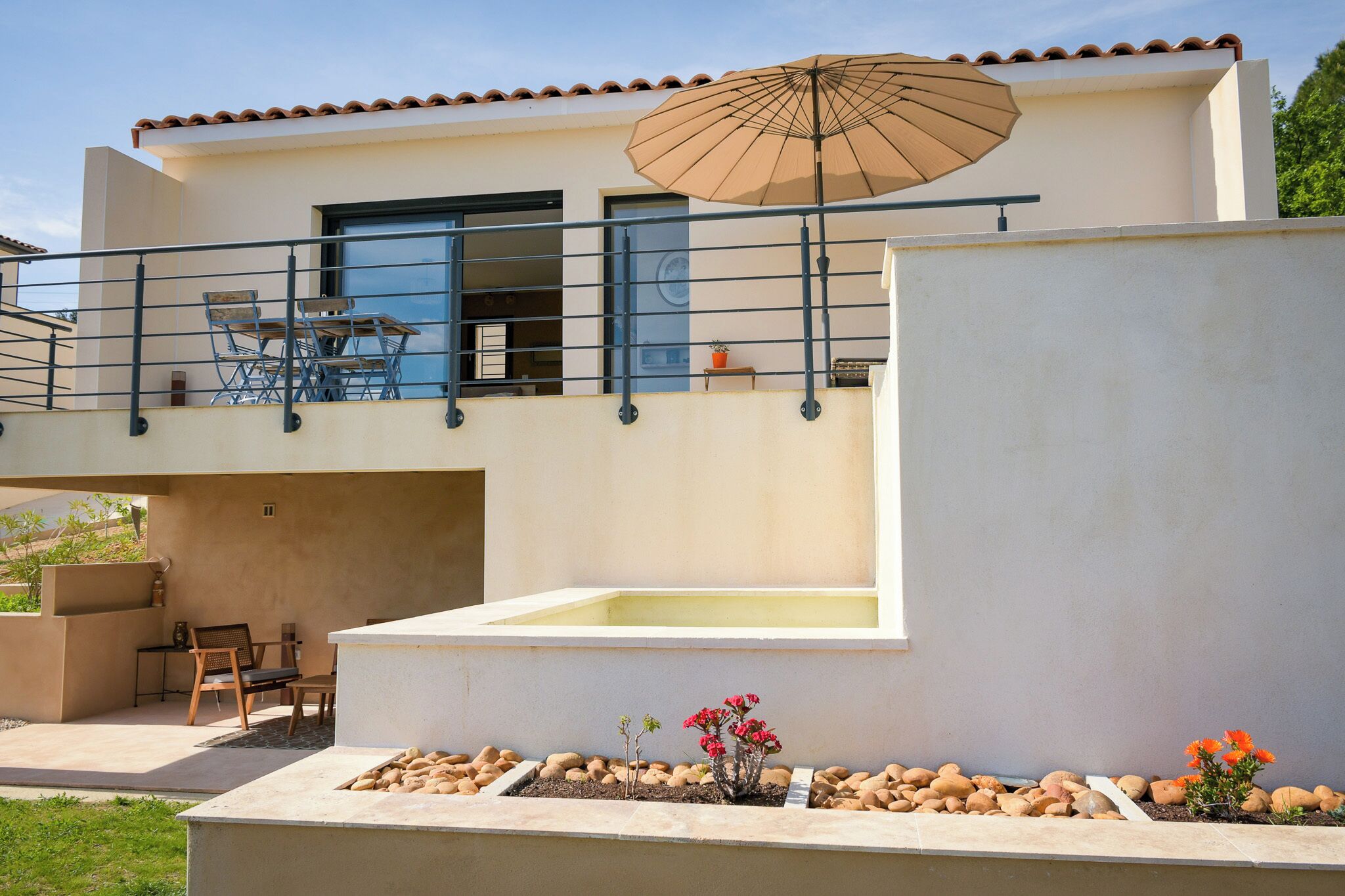 A modern two-story house with a balcony, outdoor seating, and a pool.