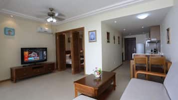 A living room with a television, a sofa, a coffee table, and a dining area with chairs.