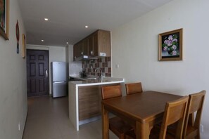 A compact kitchen with a refrigerator, wooden cabinets, and a tiled backsplash. - Shili Renjia Apartment (Huidong Yapojiao Flagship Store) (Huidong)
