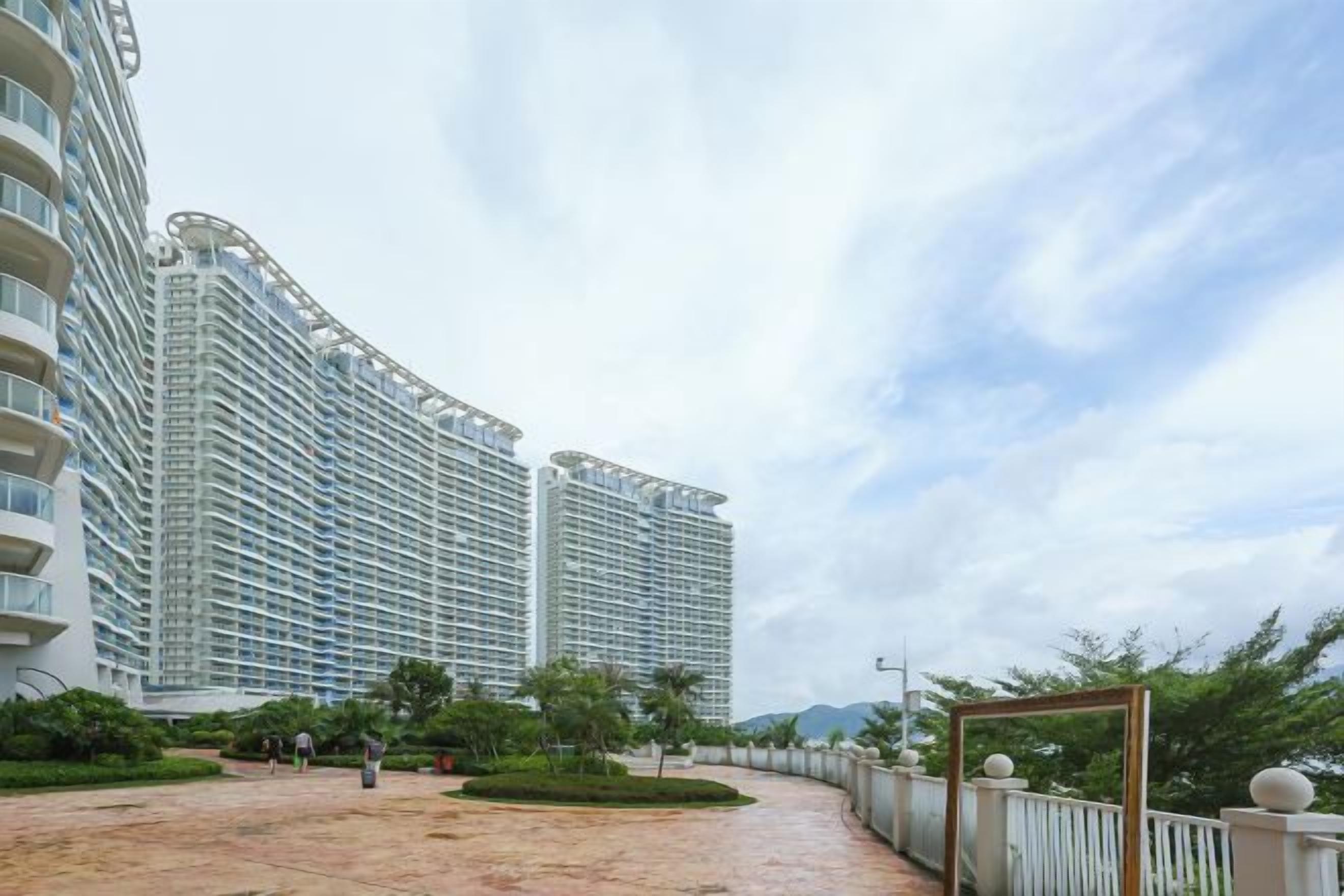 Um hotel moderno com fachada curva, um pátio amplo e céu claro.