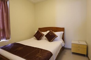 A hotel room with a bed, two pillows, a nightstand, and a window with curtains. - Shili Renjia Apartment (Huidong Yapojiao Flagship Store) (Huidong)