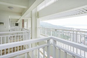 Espacio interior de varios niveles con barandas blancas, una escalera y vistas a un paisaje urbano.