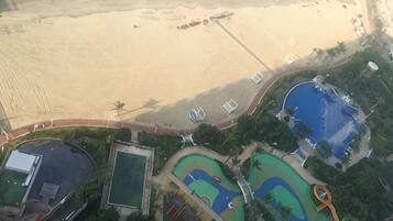 Vista aérea de un resort con playa, piscinas y un parque infantil.