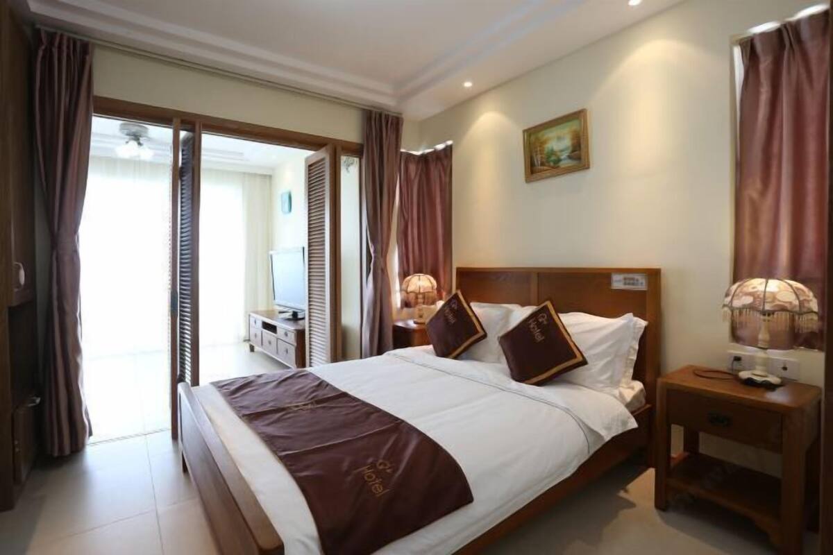 Habitación de hotel con una cama grande, dos mesitas de noche con lámparas, un cabecero de madera y un cuadro en la pared.