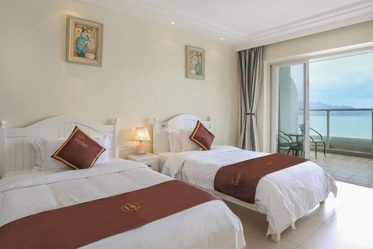 Una habitación de hotel con dos camas, un balcón con vistas y obras de arte en las paredes.