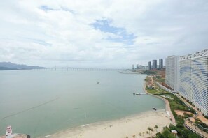 A coastal view with a bridge, beach, and high-rise buildings.
