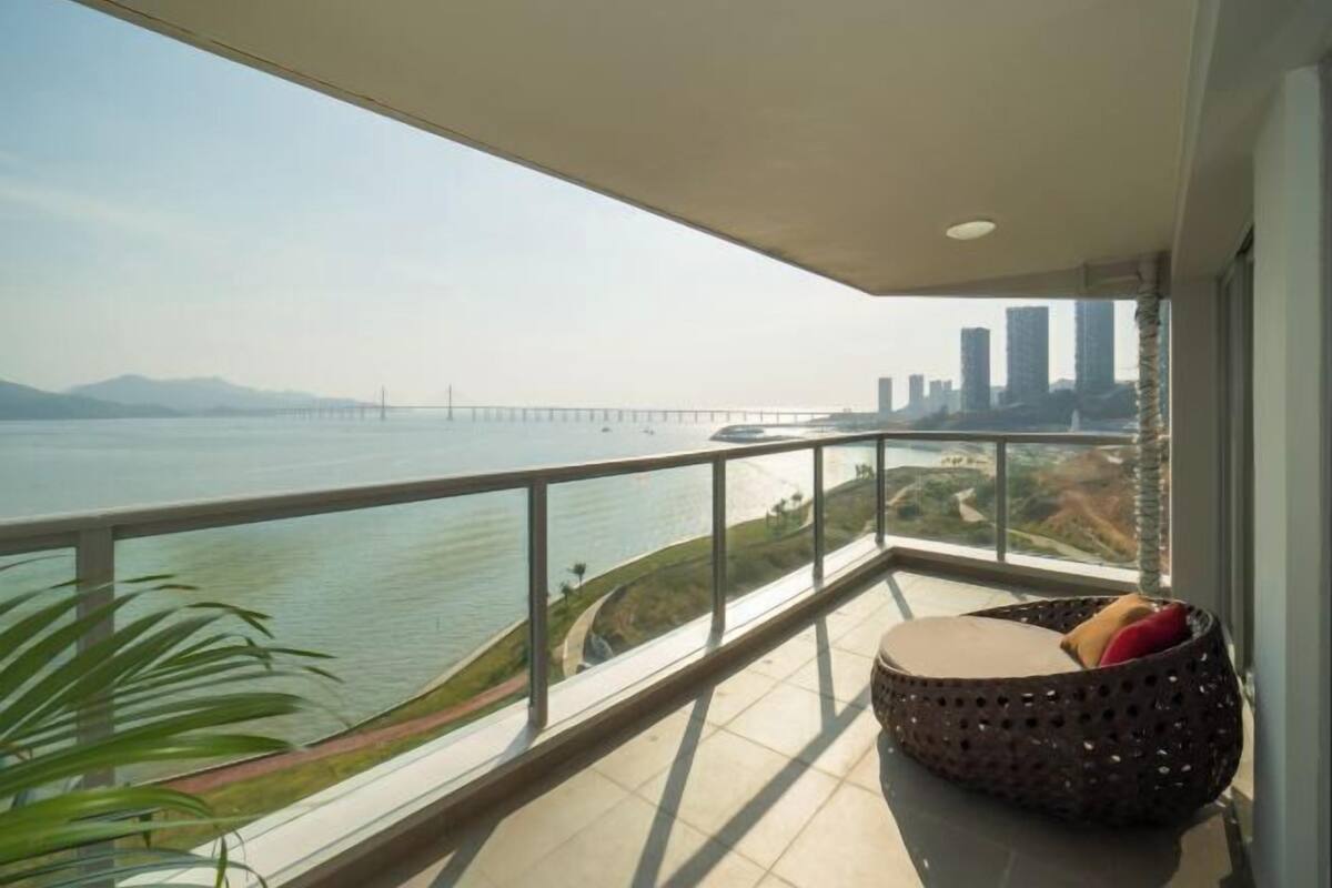 Un balcón con vistas a un puente y al horizonte urbano sobre un cuerpo de agua.