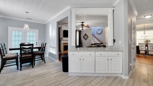 Una cocina amplia con armarios blancos, una isla central y un comedor con sillas de madera oscura y una mesa.