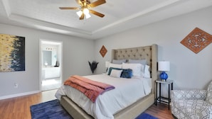 Un dormitorio con una cama grande, un ventilador de techo y una mesita de noche con lámpara.