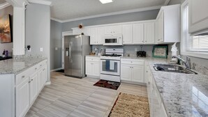 Una cocina con armarios blancos, un refrigerador de acero inoxidable, un microondas y una estufa.