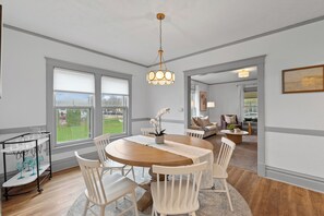 Een eethoek met een ronde houten tafel, witte stoelen en een hanglamp.
