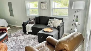 A living room with a sofa, a coffee table, a leather armchair, a floor lamp, and a rug.
