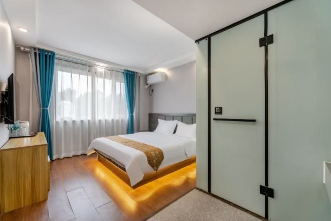 Une chambre d’hôtel moderne, équipée d’un lit, d’une table de chevet et d’une armoire.