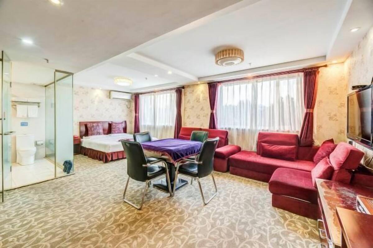 Une chambre d’hôtel avec un lit, une table à manger avec des chaises, un canapé rouge et un téléviseur.