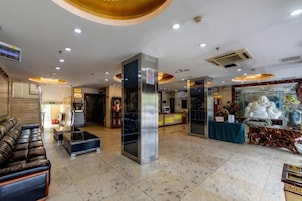 Un vestíbulo de hotel con mostrador de recepción, zona de estar y una estatua.