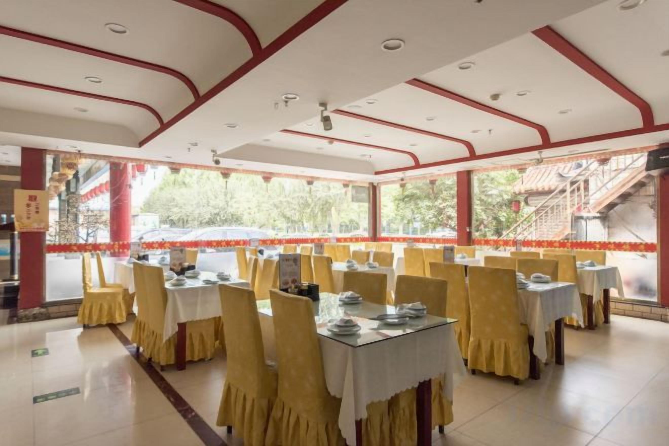 Un restaurante con mesas dispuestas para comer, piso de baldosas y vistas al exterior.