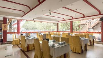 Un restaurante con mesas dispuestas para comer, piso de baldosas y vistas al exterior.