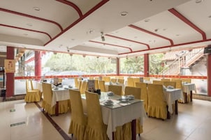 Un restaurante con mesas dispuestas para comer, piso de baldosas y vistas al exterior.