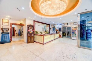Un vestíbulo de hotel con mostrador de recepción, una araña y un escaparate de vidrio.