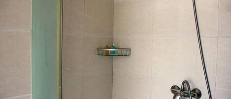 A shower area with a handheld showerhead and a wall-mounted faucet.