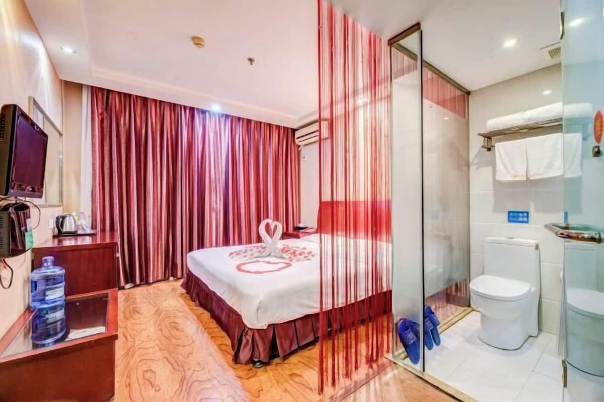 Une chambre d’hôtel équipée d’un lit, d’une douche, de toilettes, d’une télévision et d’un distributeur d’eau.