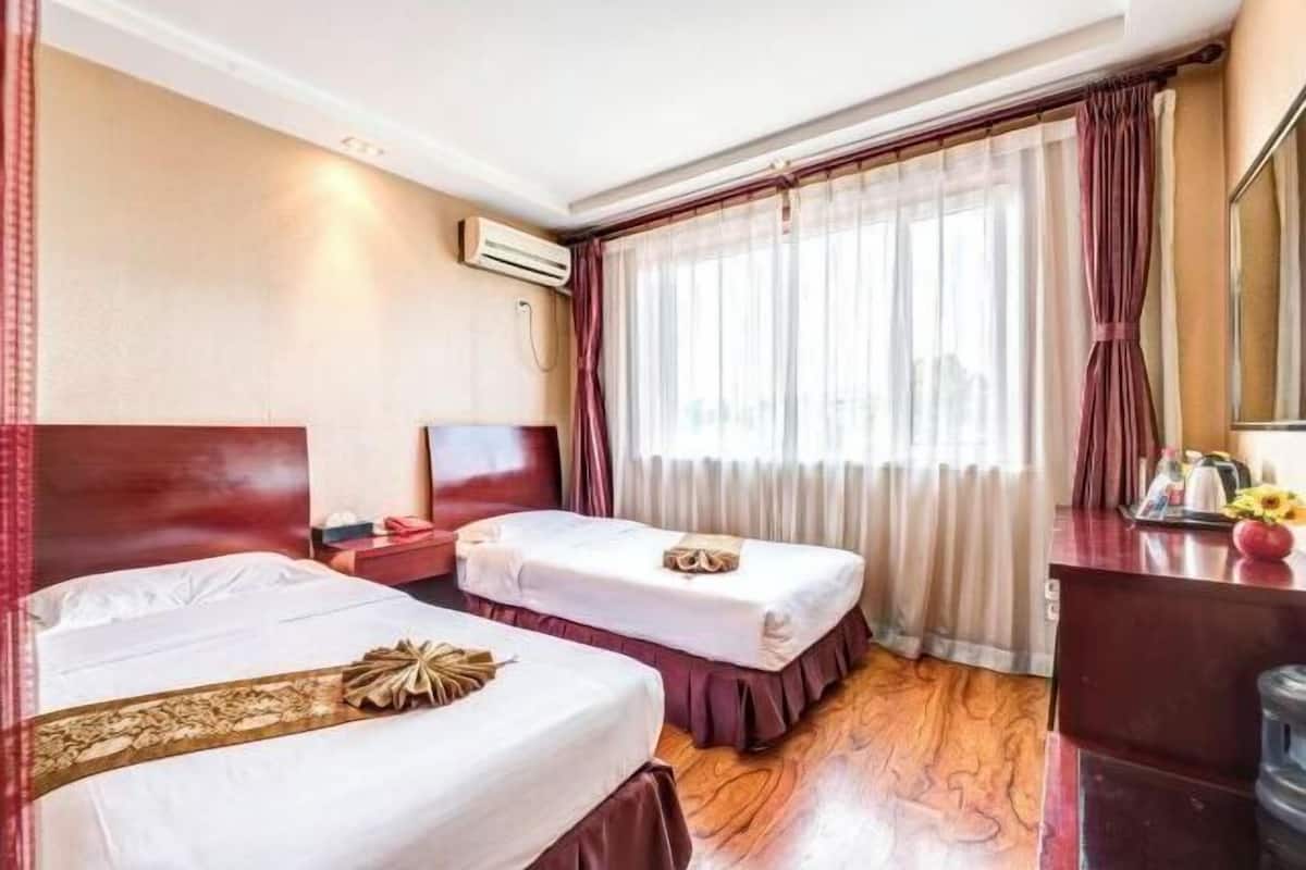 Une chambre d’hôtel avec deux lits, un bureau, un miroir et une fenêtre avec des rideaux.