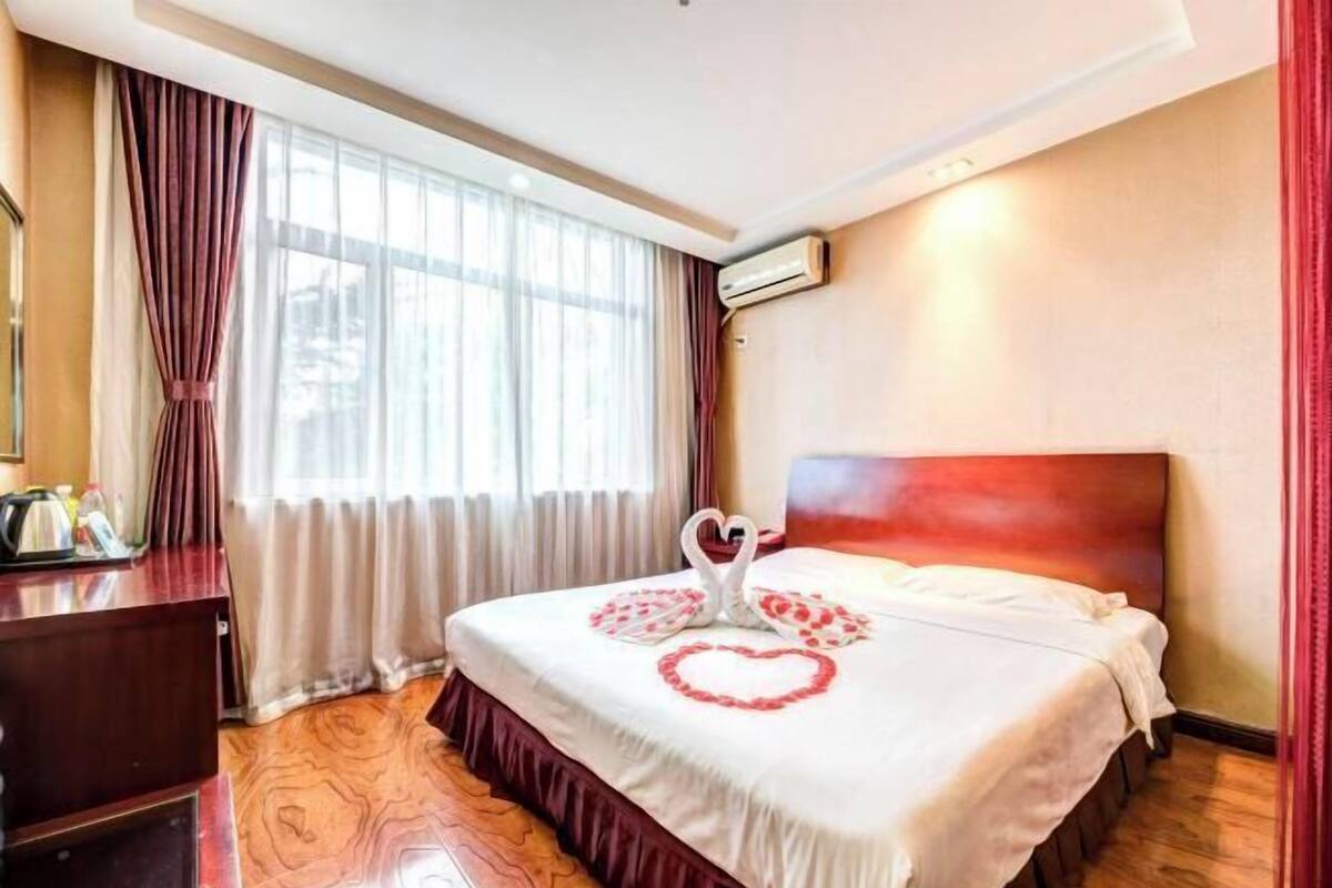 Une chambre d’hôtel avec un lit, un bureau et une fenêtre avec des rideaux.