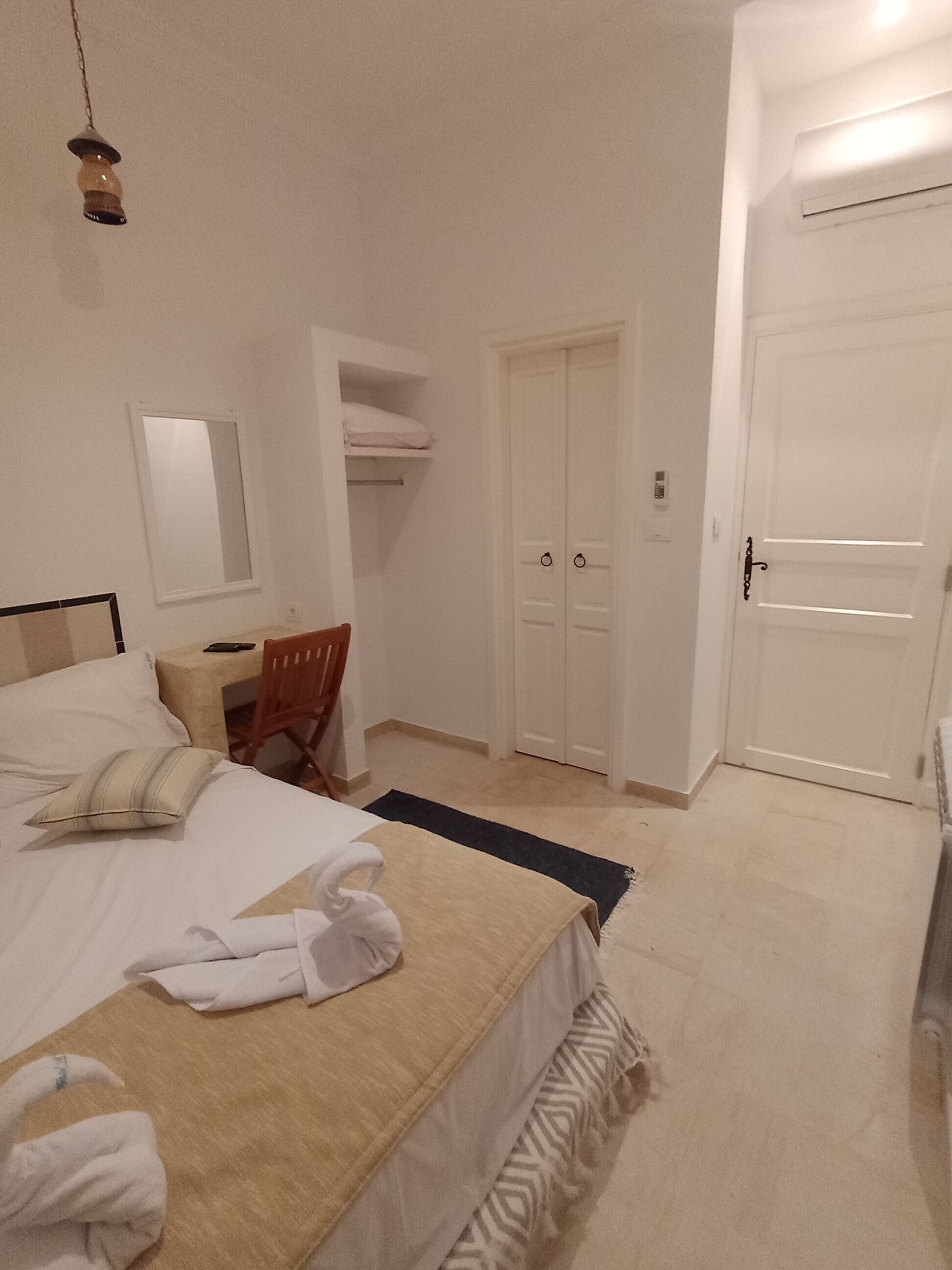 Ένα υπνοδωμάτιο με ένα κρεβάτι, ένα γραφείο, μια καρέκλα, μια ντουλάπα και μια πόρτα.