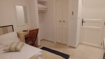 A bedroom with a bed, a desk, a chair, a wardrobe, and a door.