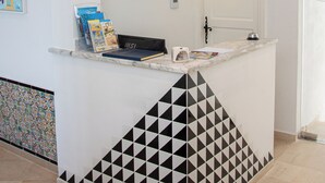 A reception desk with a white and black geometric design, a framed painting, and a wall-mounted light fixture. - Hotel Al Jazira (Mahdia)