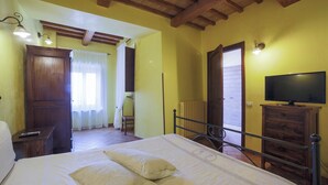Une chambre à coucher avec un lit, une armoire en bois, une télévision et une petite table avec une télécommande.