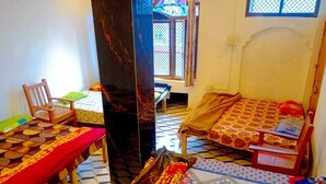 Ein Zimmer mit zwei Betten, einem Sessel, einem Tisch und einem Fenster.