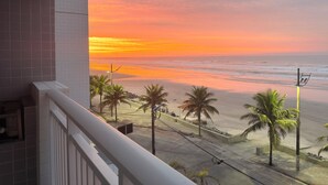 Ein Balkon mit Blick auf Strand und Meer bei Sonnenuntergang.