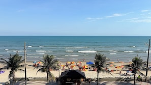 Een strand met palmbomen, parasols en een klein hutje.