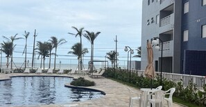 Un espace piscine avec des chaises longues et une vue sur l’océan.