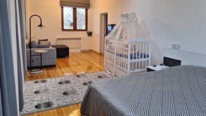 Een moderne slaapkamer met een houten plafond, een bed met een beddengoed met een patroon, een wit ledikant met hemelbed, een bank, een kleine tafel en een vloerlamp.