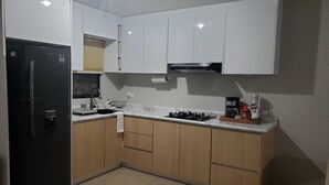 A modern kitchen with white cabinets, a black refrigerator, a gas stove, and a coffee maker.