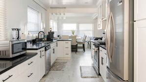 A modern kitchen with white cabinetry, stainless steel appliances, and a central island. - Hideaway Haven near LAX, Sofi Stadium, the Forum. (Inglewood)