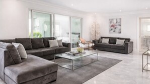 A modern living room with two grey sofas, a glass coffee table, and a minimalist decor. - Hideaway Haven near LAX, Sofi Stadium, the Forum. (Inglewood)