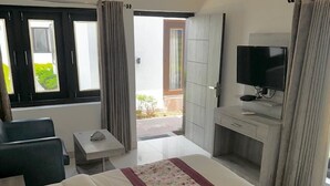 Une chambre d’hôtel avec un grand lit, une télévision, un petit bureau et une vue sur l’extérieur.
