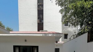 Un bâtiment à la façade blanche, doté d’un porche carrelé et d’un chemin menant à l’entrée.