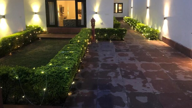 Un chemin bien éclairé mène à une maison moderne, dont l’entrée est clairement visible, et qui est agrémentée d’un petit jardin.