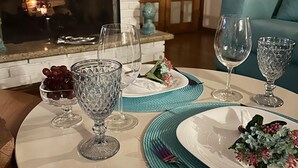 A dining area with a fireplace, a table set with plates, glasses, and a vase of flowers. - Pousada Blue Village (Campos do Jordão)