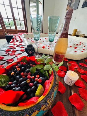 Ein Tisch mit einer Schüssel Beeren, zwei Gläsern, einer Flasche und einer Kerze.