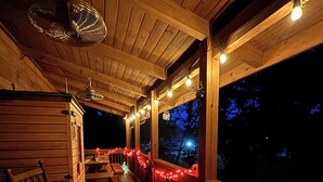 Une terrasse en bois, décorée de guirlandes lumineuses, avec une table et des chaises.