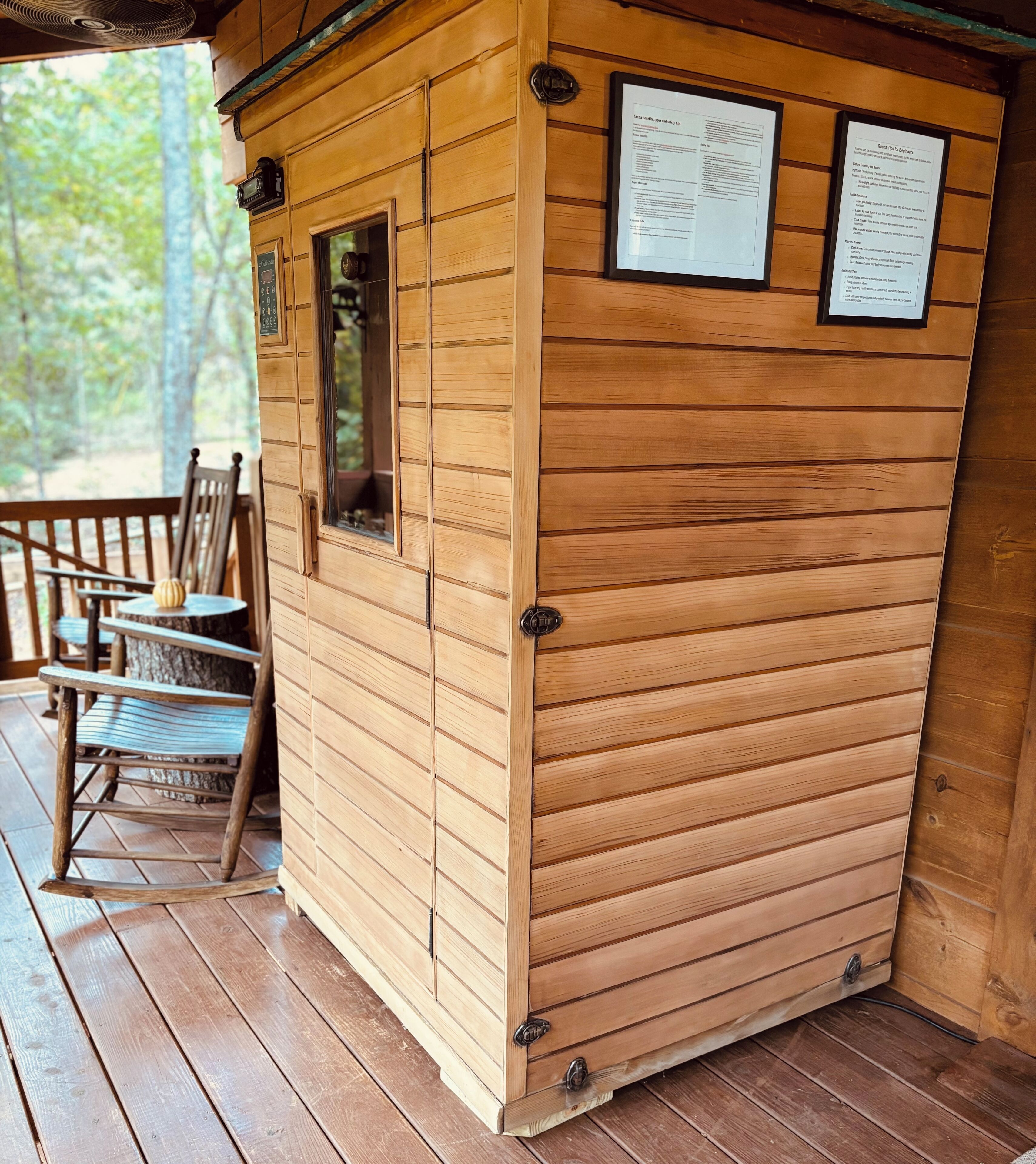 A wooden cabin with a porch, a rocking chair, and two informational signs.