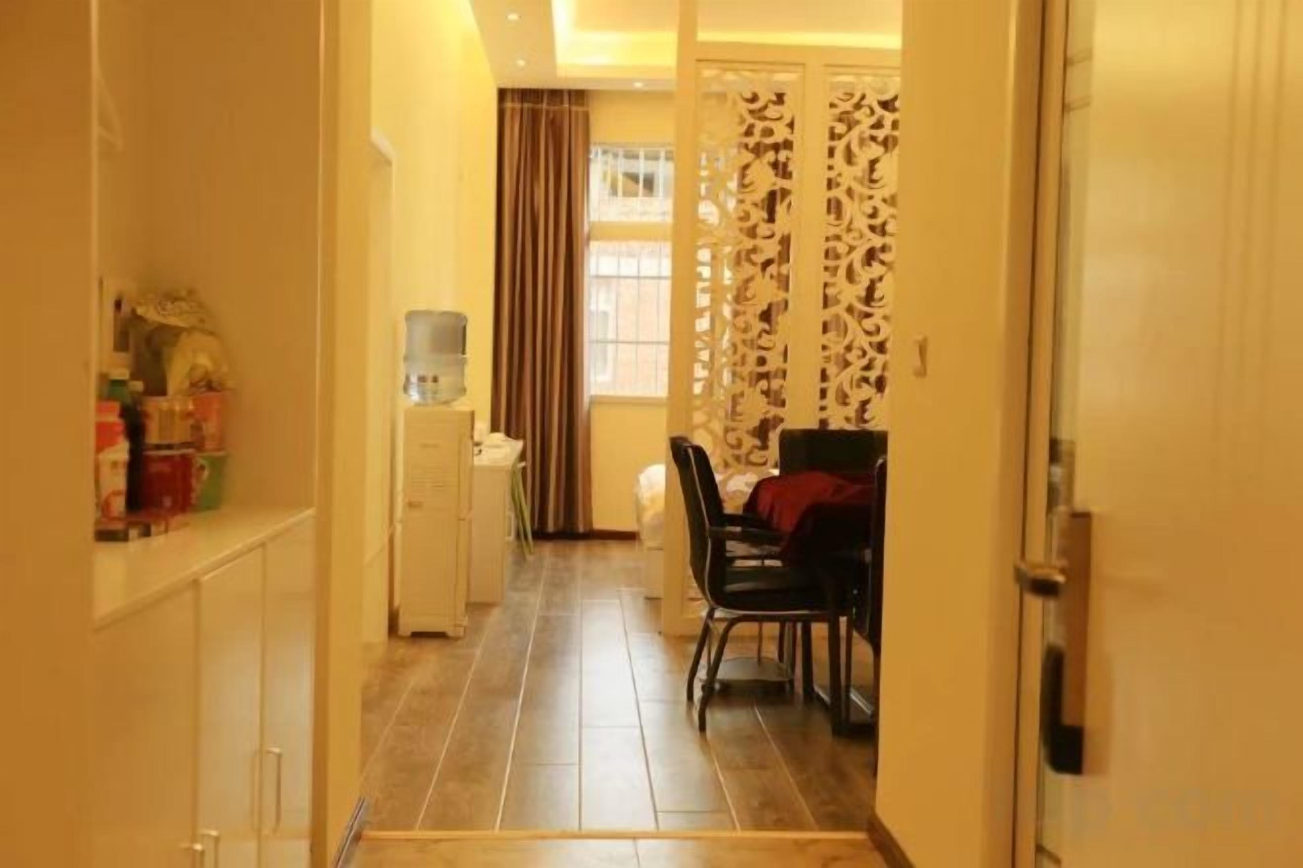 A hallway with a dining area, a water dispenser, and a door with a patterned curtain.