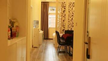 A hallway with a dining area, a water dispenser, and a door with a patterned curtain.
