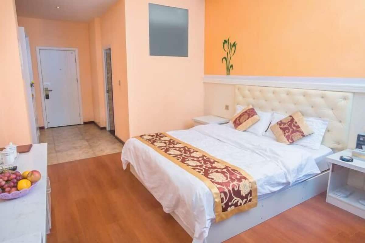 Un dormitorio con una cama, una mesita de noche, una cesta de frutas y una planta colgante en la pared.